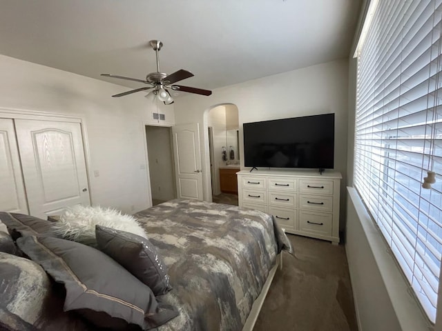 bedroom featuring visible vents, arched walkways, dark carpet, and a ceiling fan