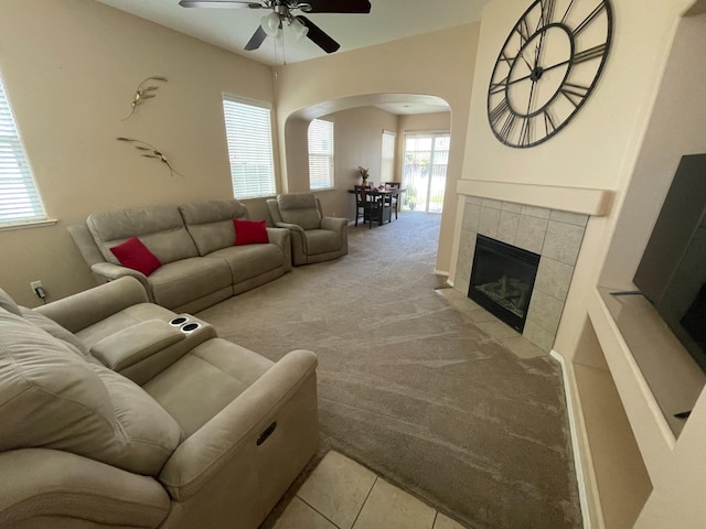 living room with arched walkways, ceiling fan, a healthy amount of sunlight, and light carpet