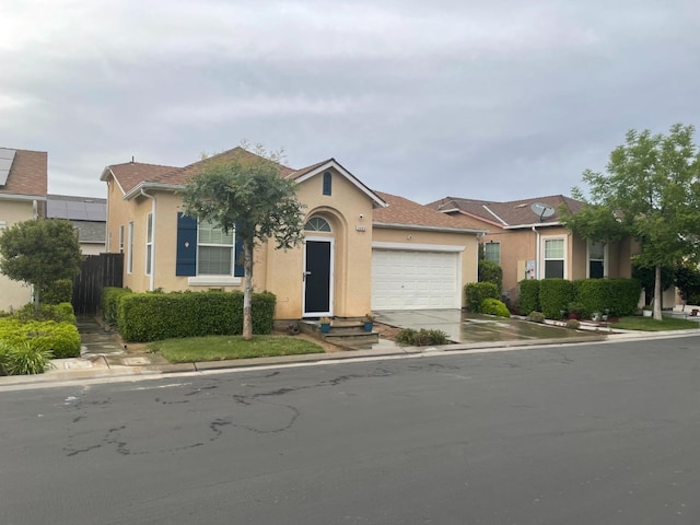 view of front of home featuring a garage, stucco siding, driveway, and fence