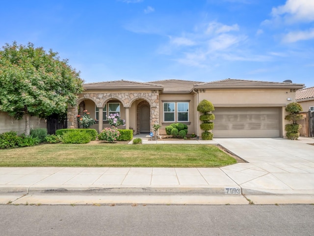 7993 N Justin Ave, Fresno, CA 93720 - view of front facade featuring a garage, stucco siding, driveway, and a front yard