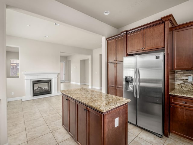 7993 N Justin Ave, Fresno, CA 93720 - kitchen featuring decorative backsplash, light tile patterned flooring, light stone countertops, stainless steel fridge, and a center island