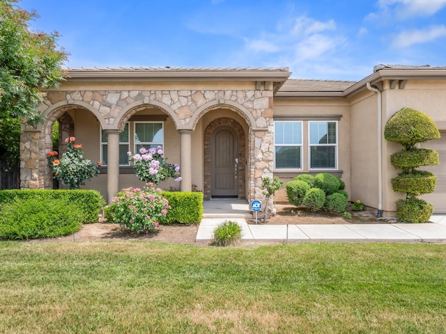7993 N Justin Ave, Fresno, CA 93720 - view of exterior entry with a yard, stone siding, and stucco siding