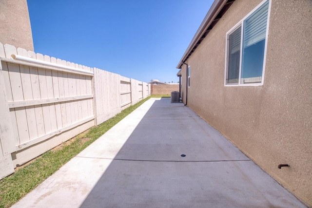 view of property exterior with a fenced backyard, central AC unit, stucco siding, and a patio