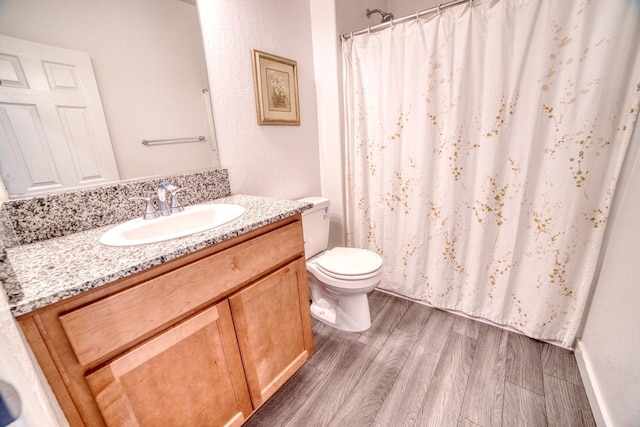 bathroom with vanity, wood finished floors, toilet, and a shower with curtain