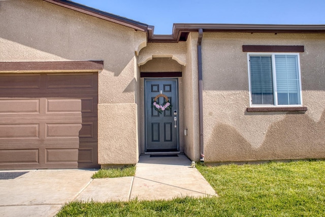 view of exterior entry featuring stucco siding and an attached garage