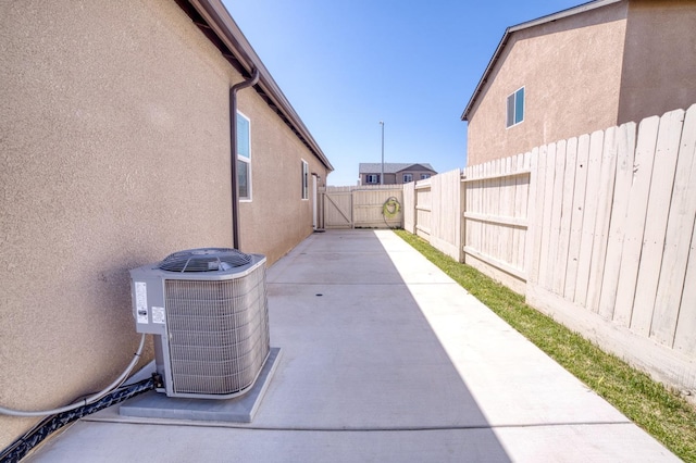 view of side of home with a fenced backyard, a patio, stucco siding, and central AC