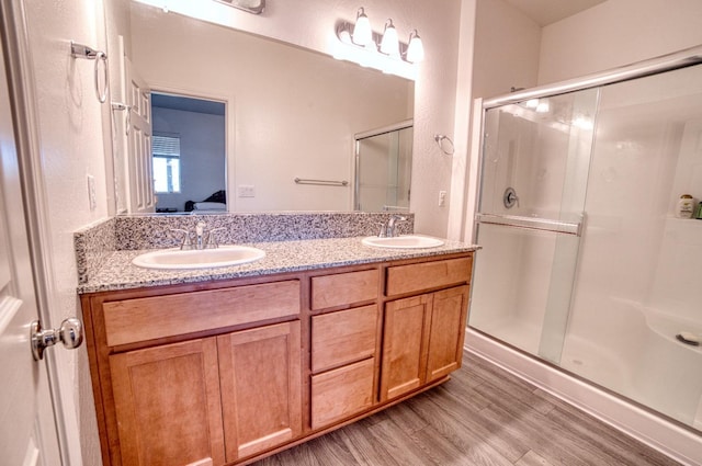 ensuite bathroom featuring wood finished floors, a sink, ensuite bath, and a stall shower