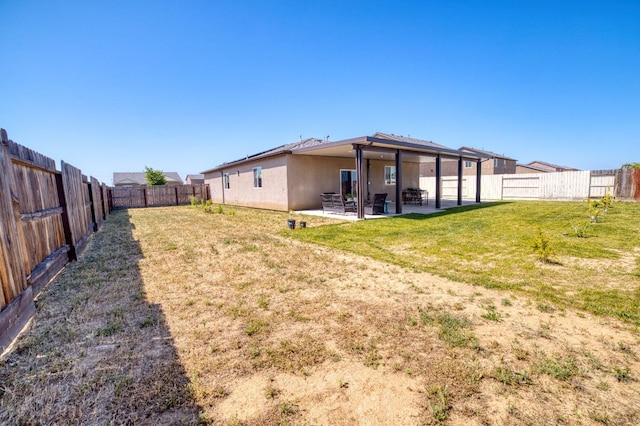 back of house featuring a fenced backyard, a patio area, stucco siding, and a yard