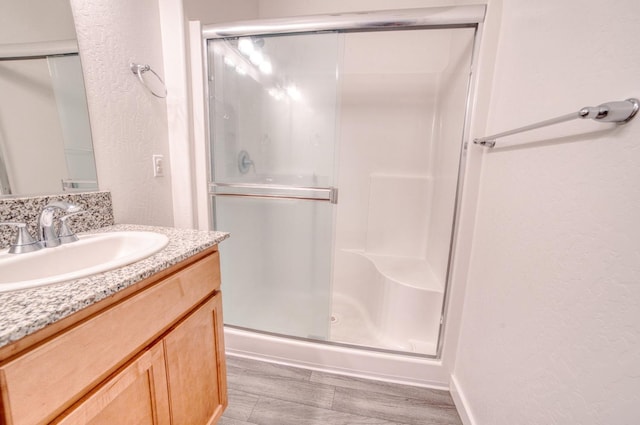 bathroom featuring vanity, a textured wall, and a shower stall