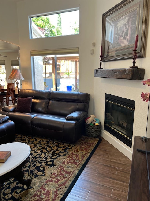 9552 N Whitehouse Dr, Fresno, CA 93720 - living area with a glass covered fireplace, wood finished floors, a towering ceiling, and ceiling fan