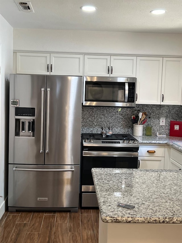 9552 N Whitehouse Dr, Fresno, CA 93720 - kitchen with stainless steel appliances, wood finish floors, white cabinetry, light stone countertops, and recessed lighting