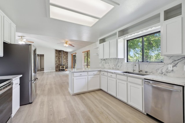kitchen featuring a sink, a peninsula, open shelves, backsplash, and stainless steel appliances