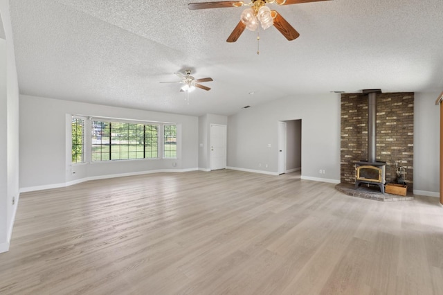 unfurnished living room featuring a wood stove, ceiling fan, and a textured ceiling