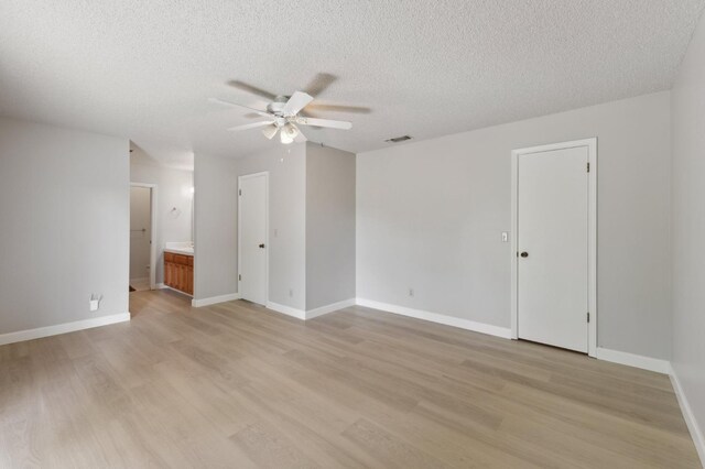 empty room featuring light wood-type flooring, a textured ceiling, a ceiling fan, and visible vents