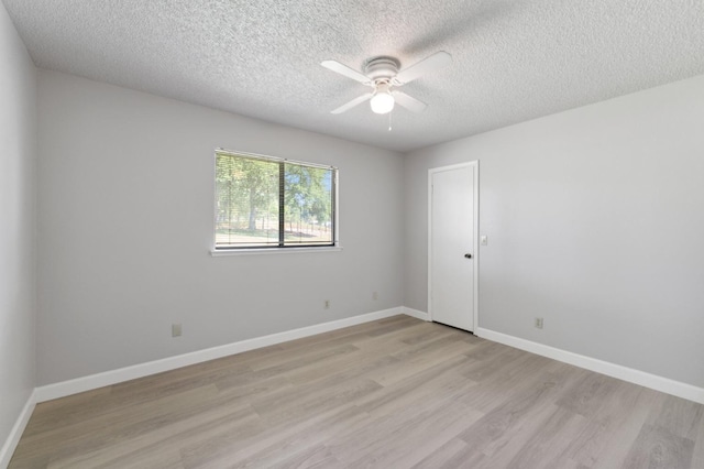 spare room featuring light wood-type flooring, baseboards, a ceiling fan, and a textured ceiling