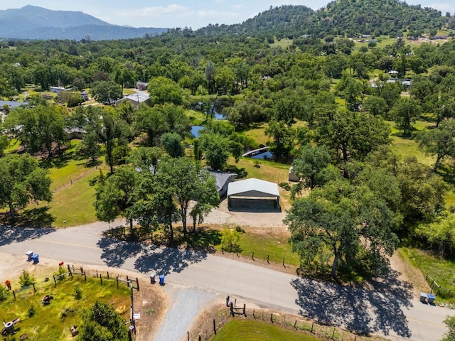 drone / aerial view with a water and mountain view and a wooded view