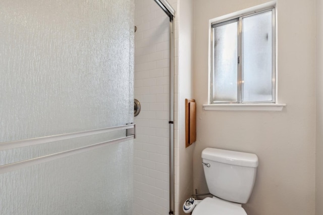 bathroom featuring a tile shower and toilet