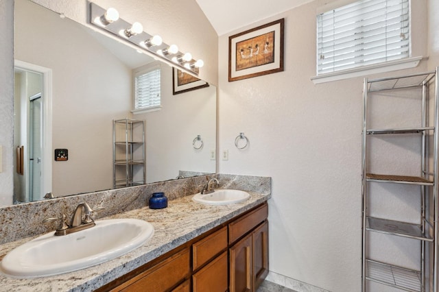 full bathroom featuring double vanity, a sink, a shower with shower door, and vaulted ceiling