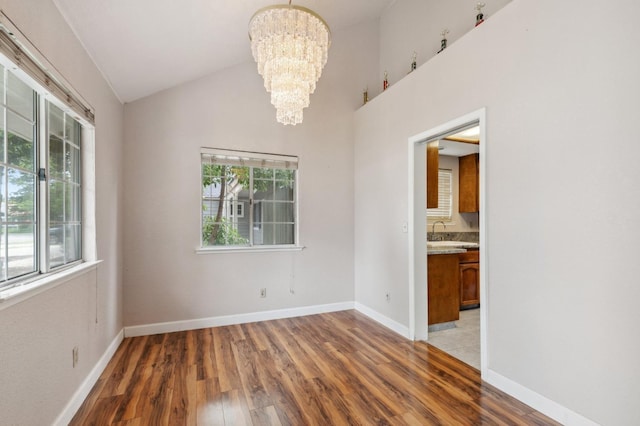 unfurnished dining area featuring baseboards, a sink, light wood-style flooring, and a notable chandelier