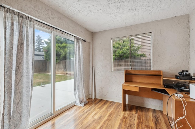 sitting room with a textured ceiling, a textured wall, wood finished floors, and a wealth of natural light