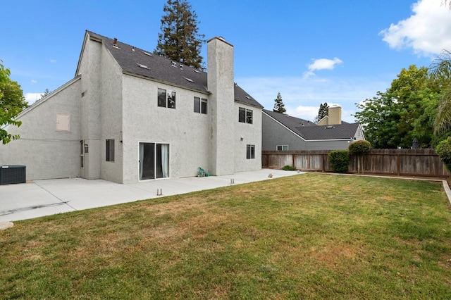 rear view of property with a chimney, a patio area, fence, a yard, and stucco siding