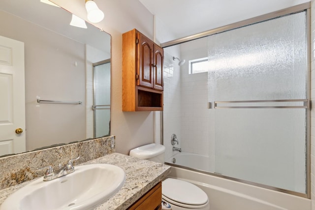 bathroom with toilet, enclosed tub / shower combo, and vanity