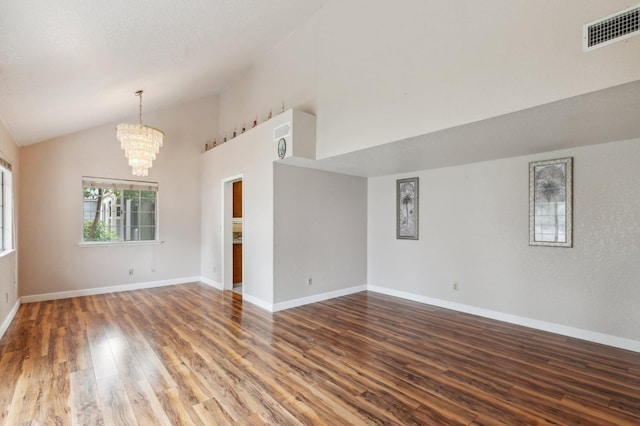 unfurnished room with baseboards, visible vents, wood finished floors, and an inviting chandelier