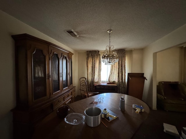 dining space featuring visible vents, a textured ceiling, and a notable chandelier