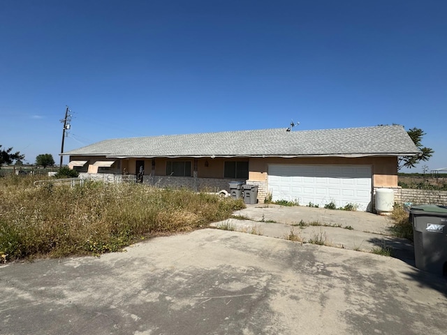 ranch-style house featuring a garage, stucco siding, and driveway