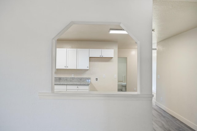 635 N San Pablo Ave, Fresno, CA 93728 - kitchen with baseboards, light countertops, light wood-style flooring, and white cabinetry