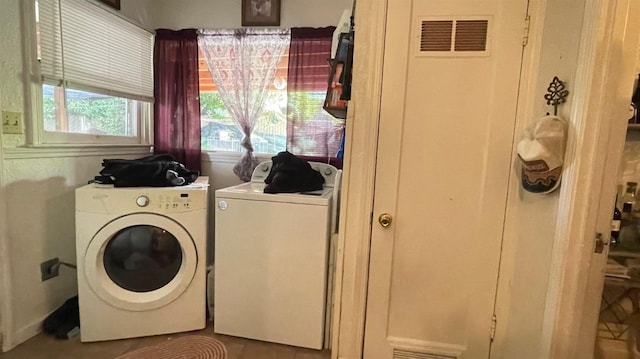 clothes washing area with laundry area, visible vents, and washer and clothes dryer