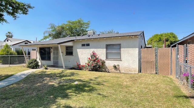 back of house with a fenced backyard, stucco siding, a yard, and central AC unit