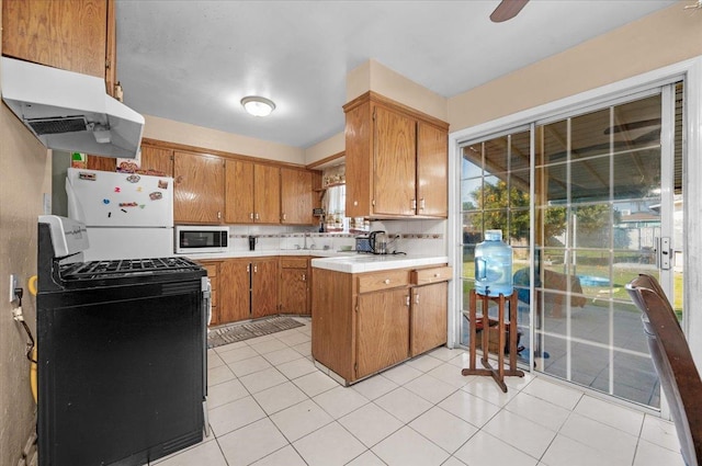 4185 E Turner Ave, Fresno, CA 93702 - kitchen with brown cabinetry, light countertops, a sink, under cabinet range hood, and white appliances