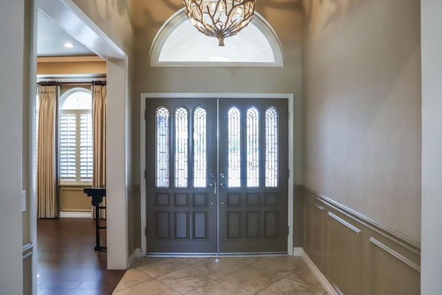 entryway with a decorative wall, a wainscoted wall, and a chandelier