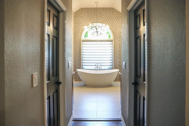 hall with baseboards, vaulted ceiling, wallpapered walls, and tile patterned flooring