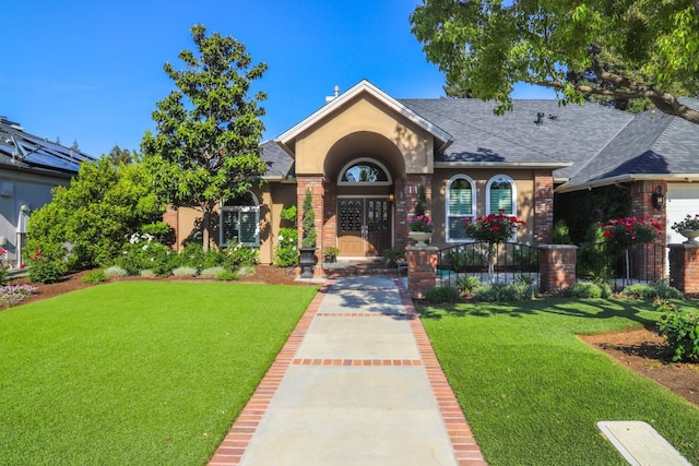 view of front of home with a shingled roof, a front yard, and brick siding