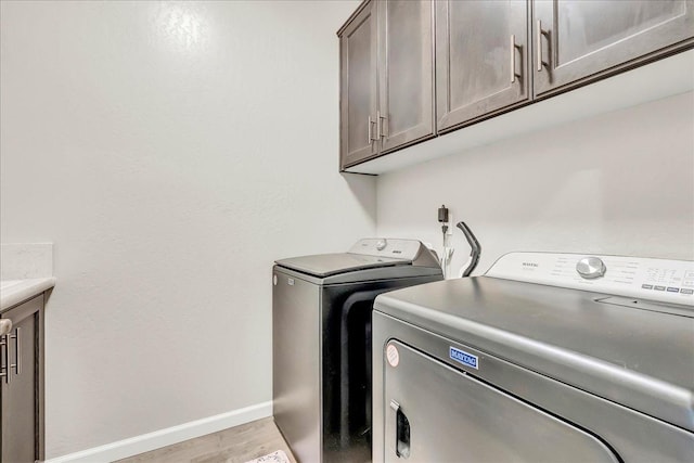 1938 W Van Gogh St, Hanford, CA 93230 - washroom with baseboards, light wood-style flooring, cabinet space, and washing machine and clothes dryer