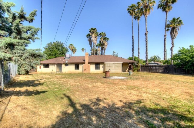 rear view of house featuring a fenced backyard and a yard