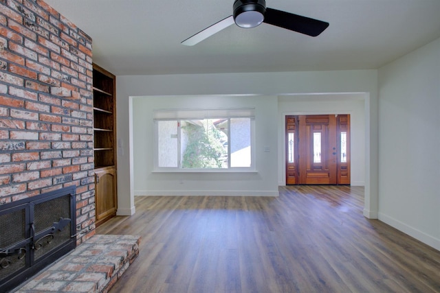 unfurnished living room featuring a ceiling fan, baseboards, wood finished floors, and a fireplace