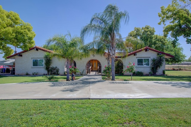 mediterranean / spanish home featuring a front lawn and stucco siding