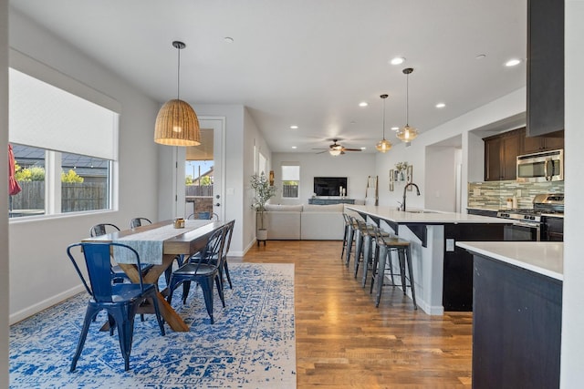 dining space with baseboards, ceiling fan, recessed lighting, and light wood-style flooring