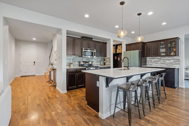 kitchen with a sink, decorative backsplash, stainless steel appliances, and dark brown cabinets