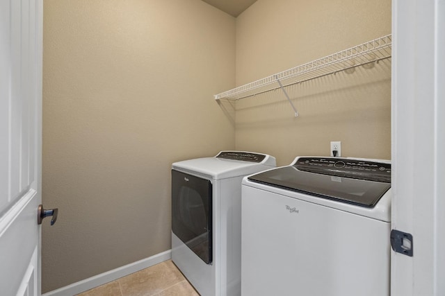 laundry area featuring baseboards, laundry area, light tile patterned flooring, and washer and clothes dryer