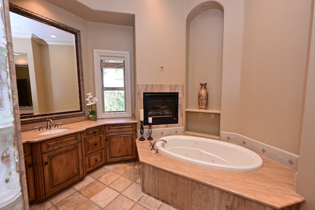 full bathroom featuring a tiled fireplace, a whirlpool tub, crown molding, and vanity
