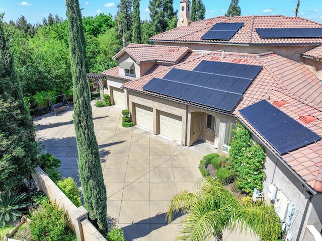 exterior space featuring roof mounted solar panels, stucco siding, a tiled roof, and driveway