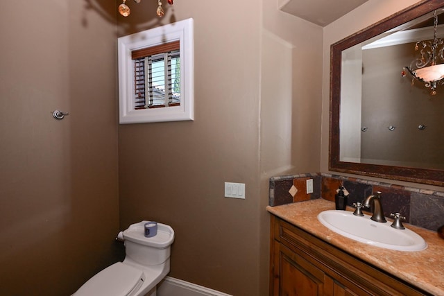 bathroom with vanity, decorative backsplash, baseboards, and toilet