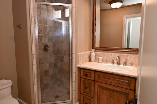 bathroom featuring vanity, backsplash, a shower stall, and toilet