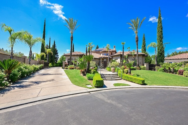 view of front of home featuring a front lawn, stucco siding, a tile roof, and fence