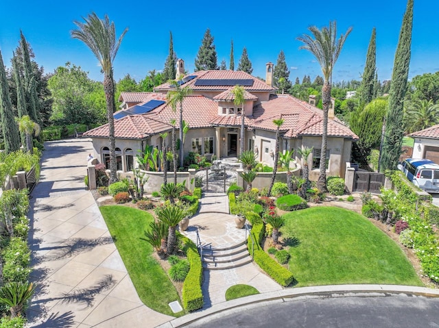 mediterranean / spanish-style home featuring a front lawn, stucco siding, a chimney, and a tile roof