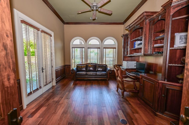 home office featuring dark wood-type flooring, ornamental molding, wainscoting, and built in desk